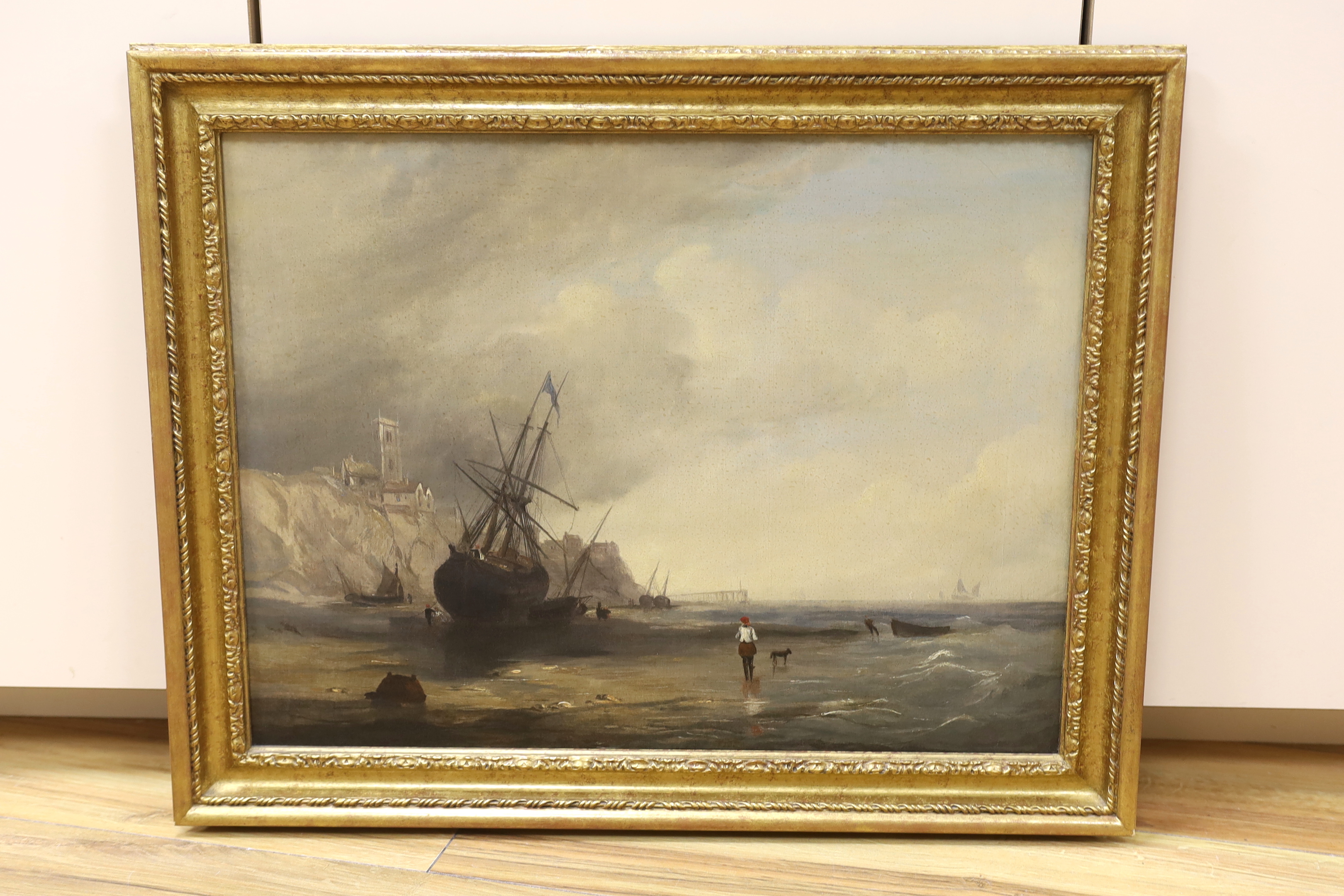 Early 19th century English school, oil on canvas, Beached fishing boats beneath a cliff top church, 39 x 52cm